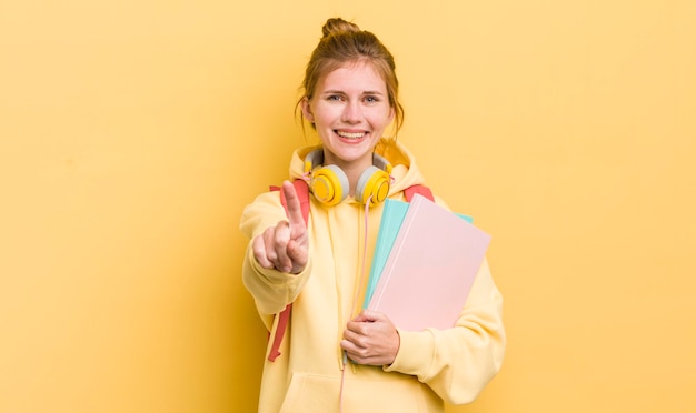 Chica guapa pelirroja sonriendo con orgullo y confianza haciendo el concepto de estudiante número uno