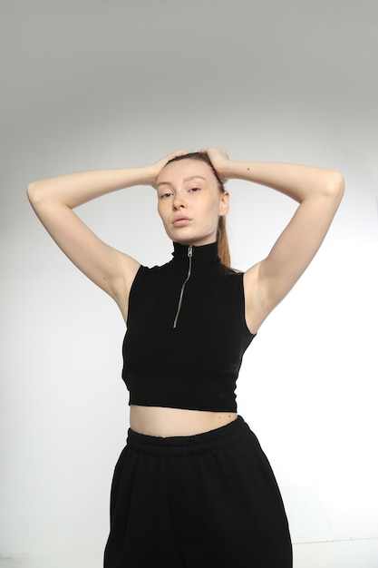 Chica guapa con pelo de jengibre Aspecto de alta moda joven y bella mujer posando en la pared blanca.