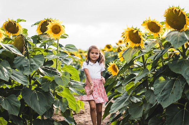 Chica guapa de pie entre girasoles