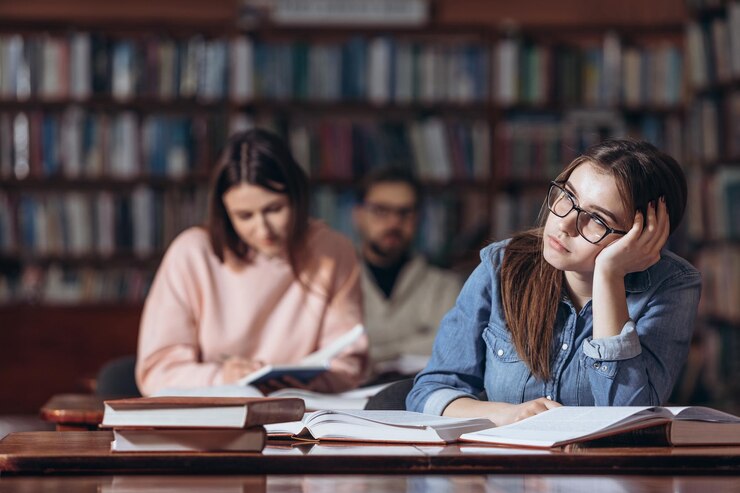Chica guapa soñando con fiesta mientras estudia en la biblioteca