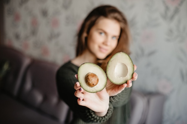 Chica guapa sosteniendo un aguacate verde cortado