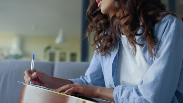 Chica con guitarra escribiendo música en casa Guitarrista haciendo notas en cuaderno