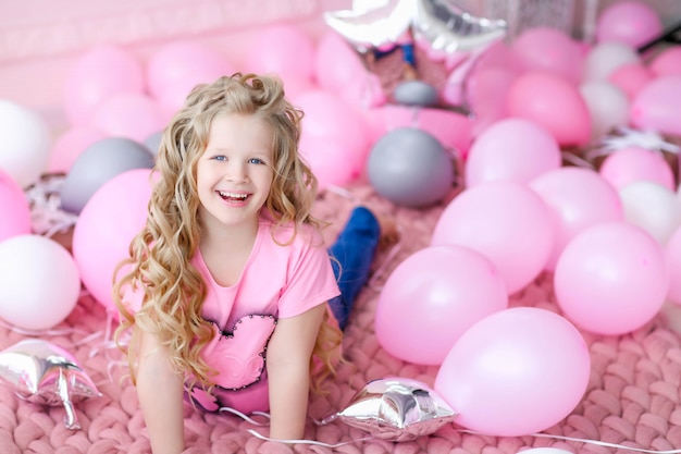 Chica en una habitación rosa y ropa rosa sobre un fondo de globos