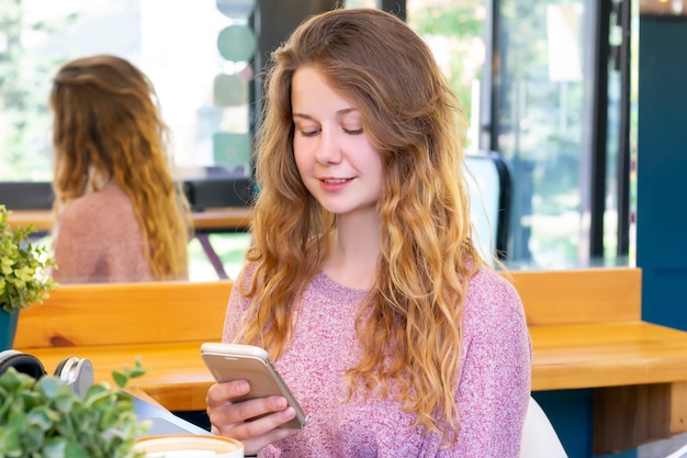 Chica habla por teléfono. niña escribe un mensaje en el teléfono.