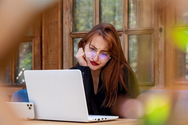 Foto la chica está hablando en un enlace de video una chica en un traje negro está hablando en una conexión de video en una computadora portátil en un café mostrando diferentes emociones
