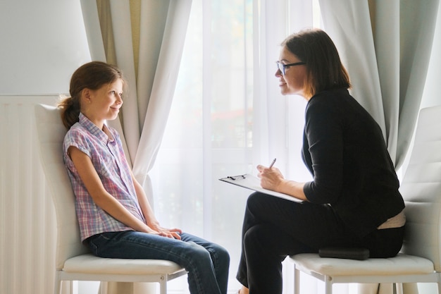 Chica hablando con psicóloga consejera discutiendo los sentimientos del niño