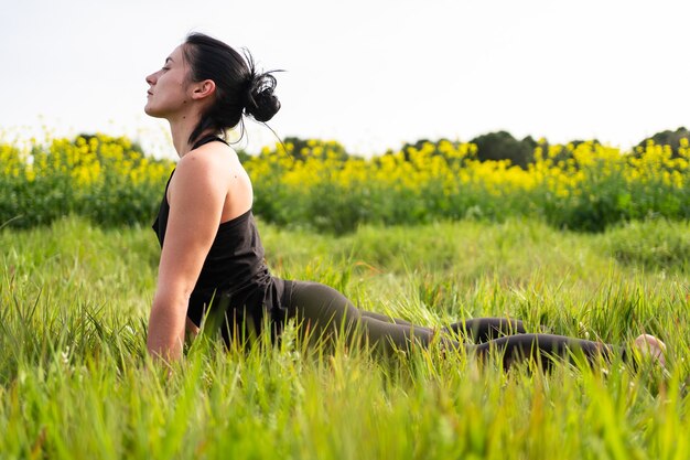 Chica hace una postura de yoga en la naturaleza.