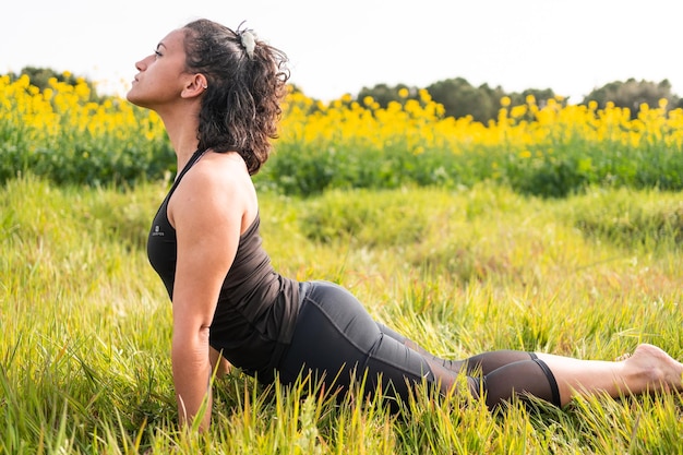 Chica hace una postura de yoga en la naturaleza.