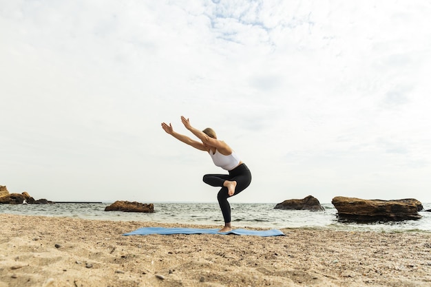 La chica hace yoga en la naturaleza cerca del mar.