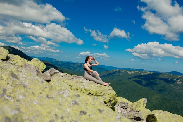 Chica haciendo ejercicio de yoga pose de loto en la cima de la montaña.