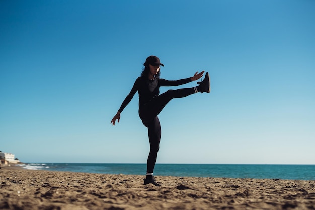 una chica haciendo ejercicios en la orilla de la mar en ropa deportiva entrenador de fitness chica haciendo ejercicio