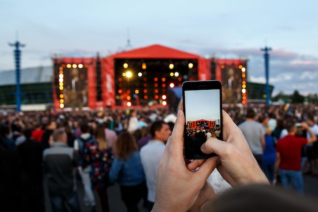 Chica haciendo fotos y videos mientras baila en un festival de música al aire libre