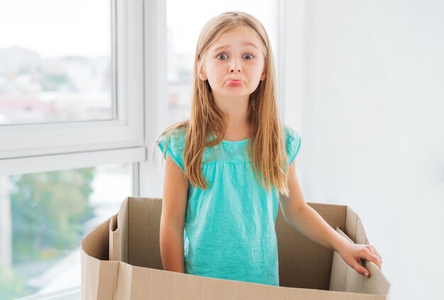 Chica haciendo una mueca triste dentro de la caja