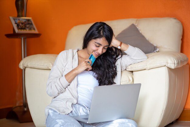 Chica haciendo pagos en línea usando una computadora portátil para comprar en casa