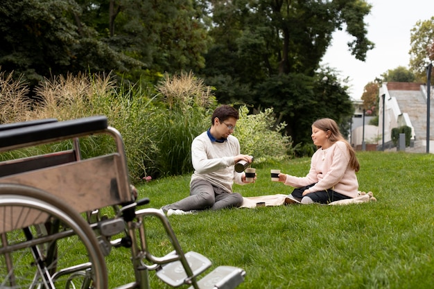 Foto chica haciendo un picnic con el hombre discapacitado