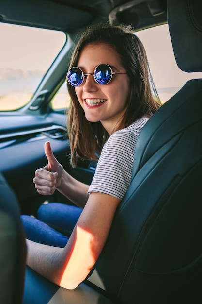 Chica haciendo pulgares arriba en el auto