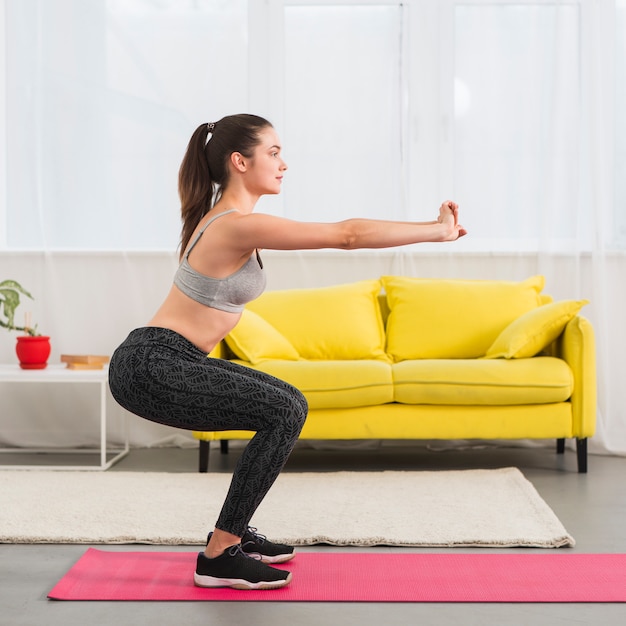 Foto chica haciendo sentadilla en su casa