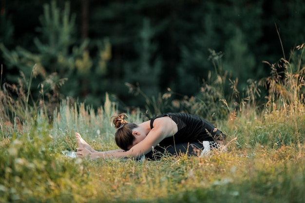 Foto la chica está haciendo yoga al aire libre. el concepto de deporte.