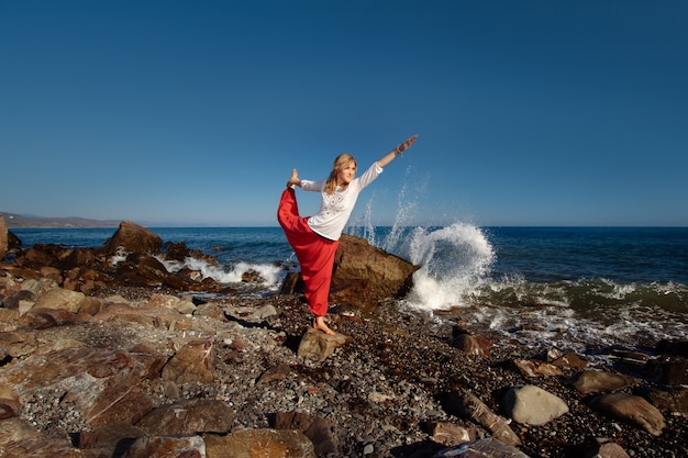 Chica haciendo yoga en la colina. Océano en olas