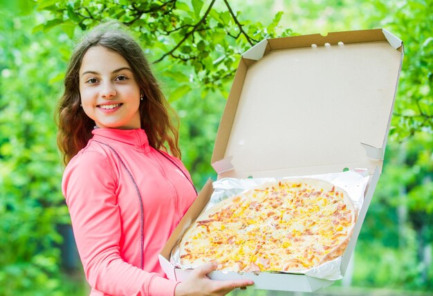 Chica hambrienta pizza caja naturaleza fondo picnic tiempo concepto