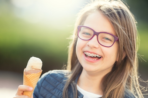 Chica con helado Joven linda chica rubia caucásica con aparatos dentales y gafas