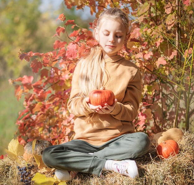 Chica en el heno con calabazas