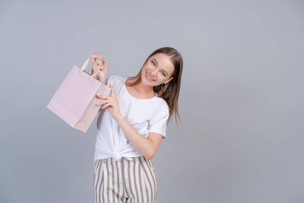 Chica hermosa alegre sosteniendo bolsa de compras con lugar para maqueta aislado