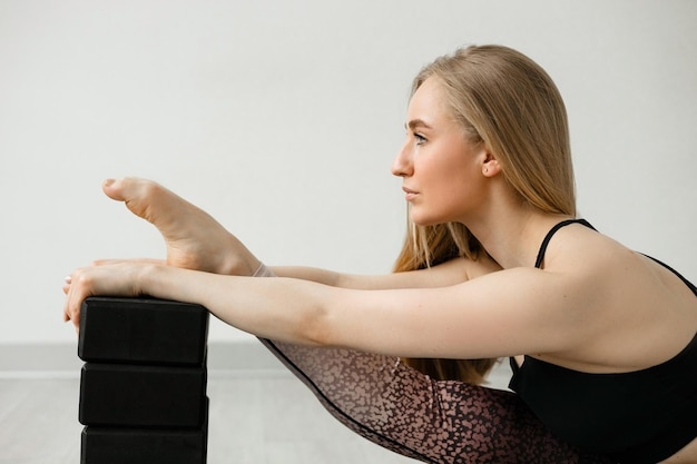 Una chica hermosa está sentada sobre un hilo en una colchoneta de fitness