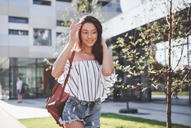 Chica hermosa, feliz joven estudiante con mochila cerca del campus de la universidad. Concepto de educación y ocio