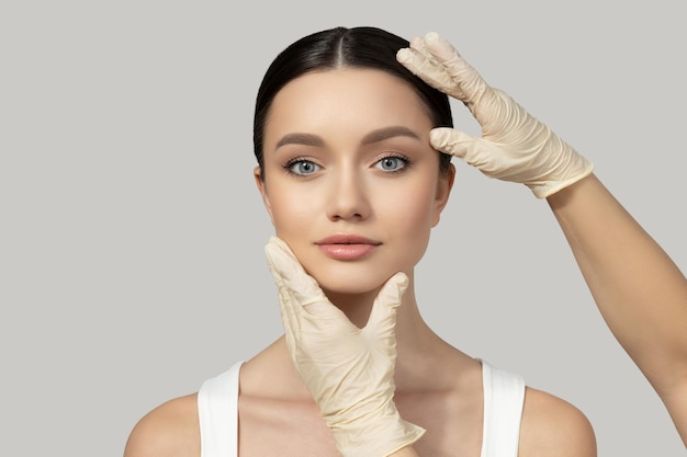Una chica hermosa hace una inyección de botox en un fondo gris