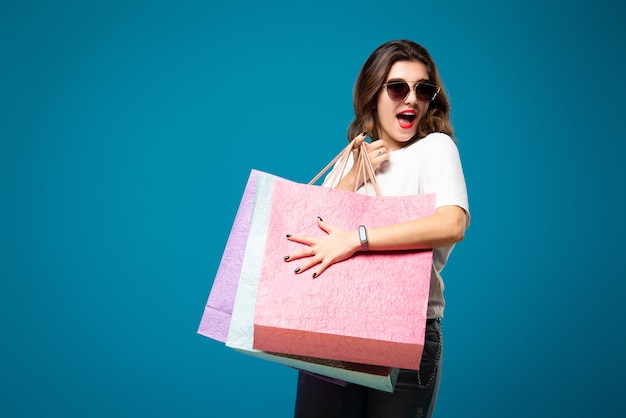 Foto chica hermosa joven elegante en gafas de sol está caminando con bolsas de compras multicolores