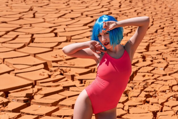 Chica hermosa joven modelo con pelo corto azul en el desierto posando