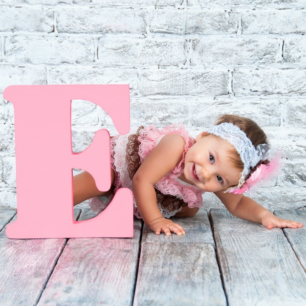 Chica hermosa y linda en vestido rosa con la letra E. Chica emocional.
