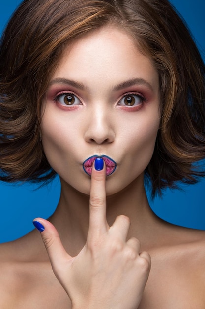 Chica hermosa modelo con maquillaje brillante y esmalte de uñas de colores Rostro de belleza Uñas cortas y coloridas