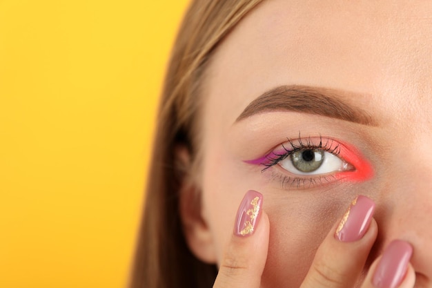 Chica hermosa modelo con maquillaje sobre fondo amarillo