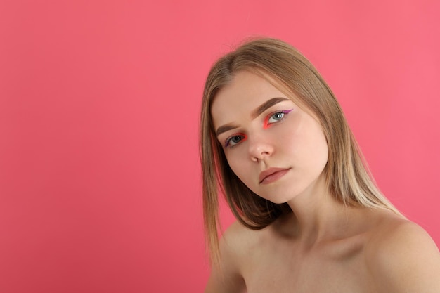 Chica hermosa modelo con maquillaje sobre fondo rosa