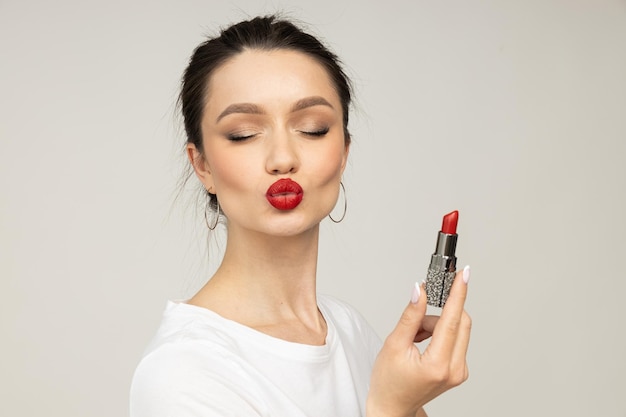 Foto una chica hermosa muestra labios rojos con pintalabios en las manos.