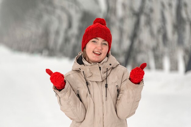 Foto una chica hermosa se ríe y muestra clase en el fondo de la nieve una mujer joven con cómoda ropa de invierno camina en el parque