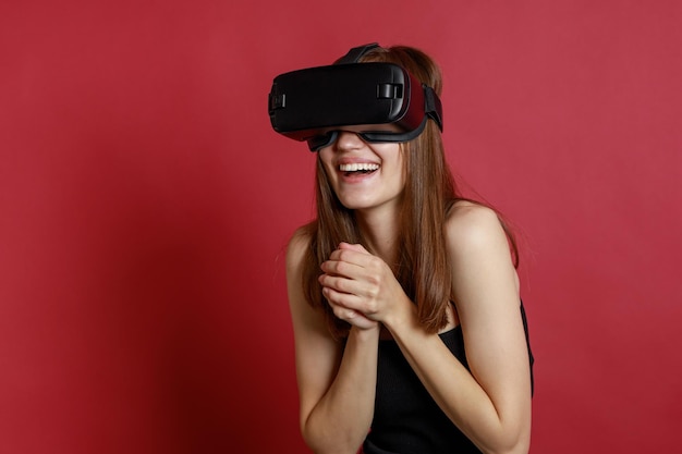 Una chica hermosa sonriente usando un set de realidad virtual y sosteniendo sus manos juntas