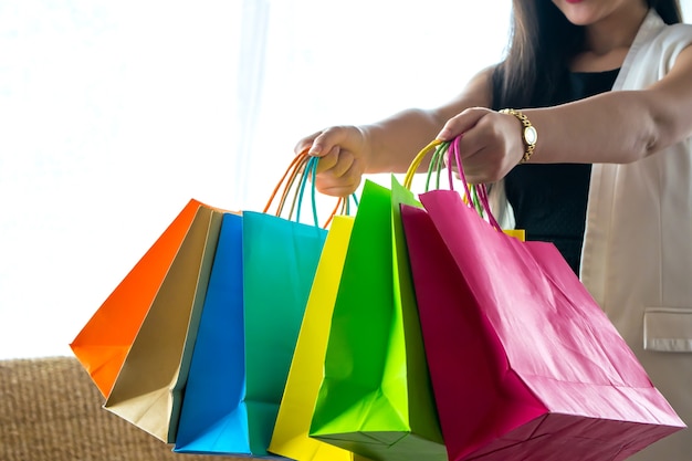 Chica hermosa sonrisa sosteniendo colorido bolso de compras y tarjeta de crédito