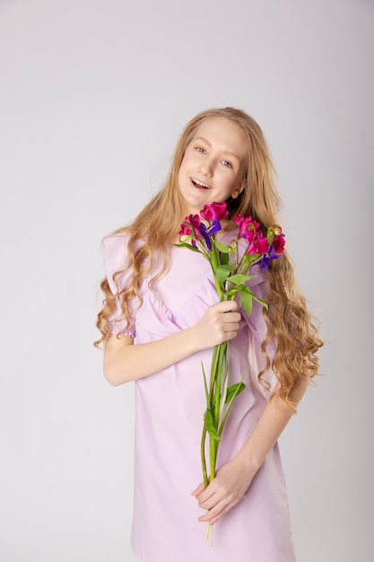 Chica con hermosas flores en ropa morada