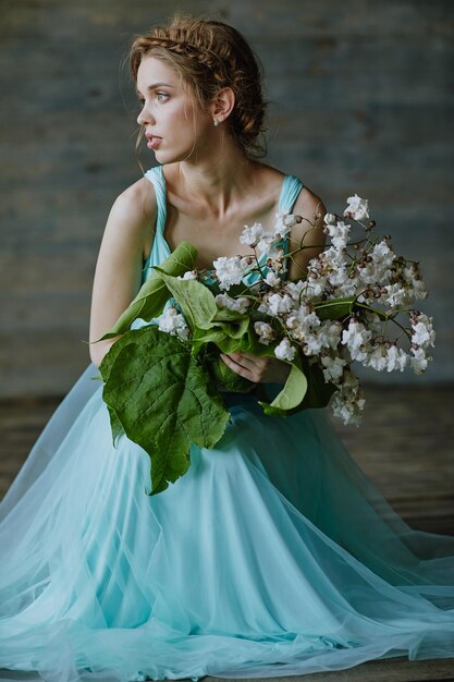 Chica con un hermoso ramo de flores en un vestido azul