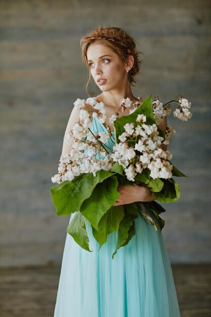 Chica con un hermoso ramo de flores en un vestido azul