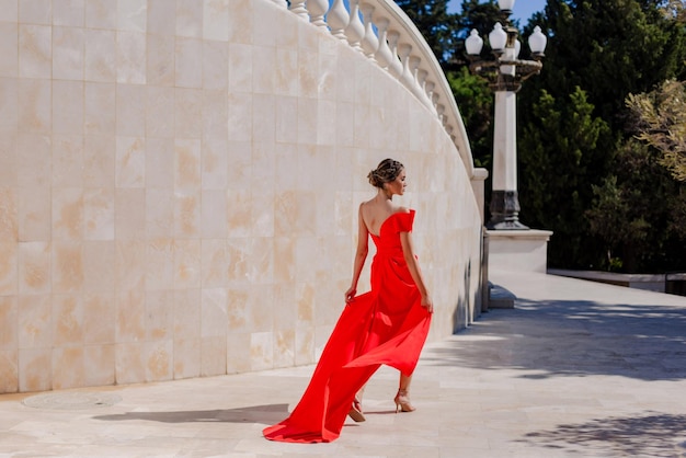 Chica con un hermoso vestido rojo elegante en el parque