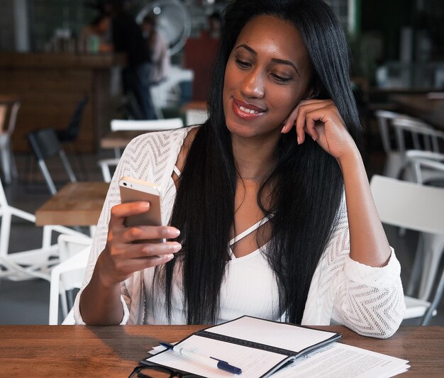 Chica hipster afroamericana alegre escribiendo para hacer la lista y