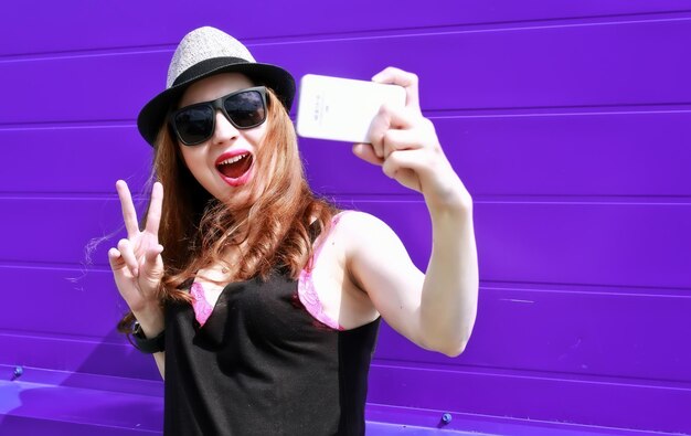 Chica hipster con auriculares en la pared