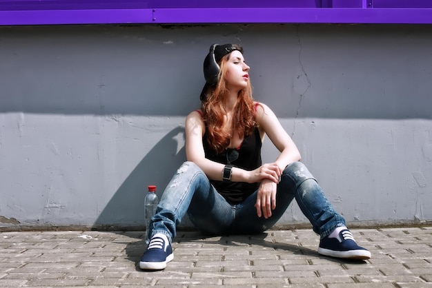 Chica hipster con auriculares en la pared