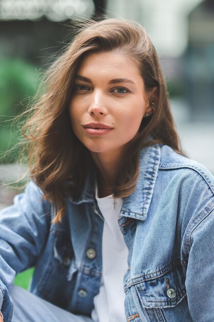 Chica hipster en camiseta blanca limpia y jeans posando contra el fondo de los edificios