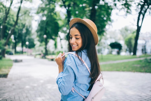 Chica hipster despreocupada con mochila de moda pasando el día para visitar el parque de la ciudad durante las vacaciones de viaje