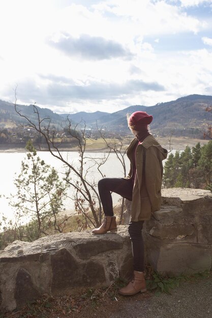 Chica hipster se sienta en el fondo de las montañas